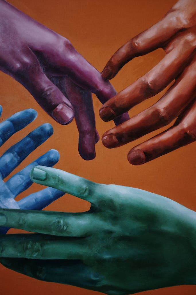 Artistic portrayal of multicolored hands on a vibrant orange background, symbolizing unity and diversity.